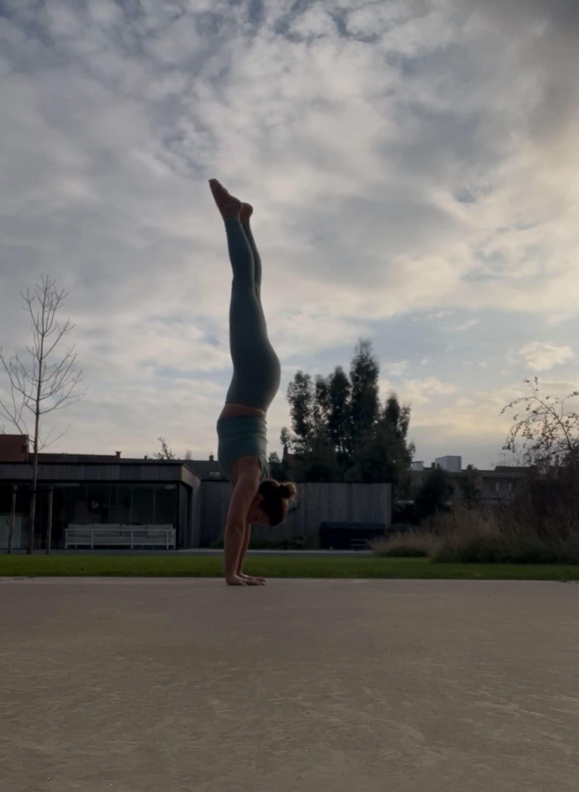 Leslie Cottenjé in een handenstand tegen een wolkendek — evenwicht als dagelijkse oefening